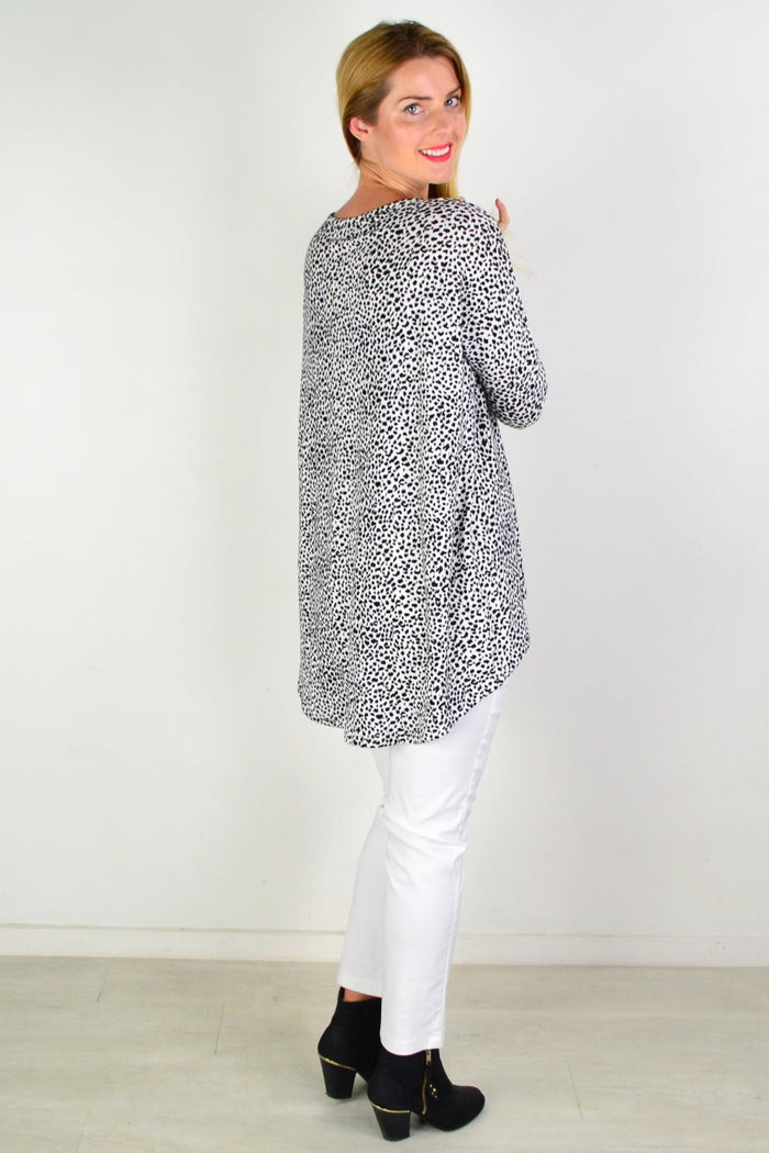 Caroline Morgan black and white spot hi-low tunic top displayed on a hanger, showcasing its pattern and flowing style.