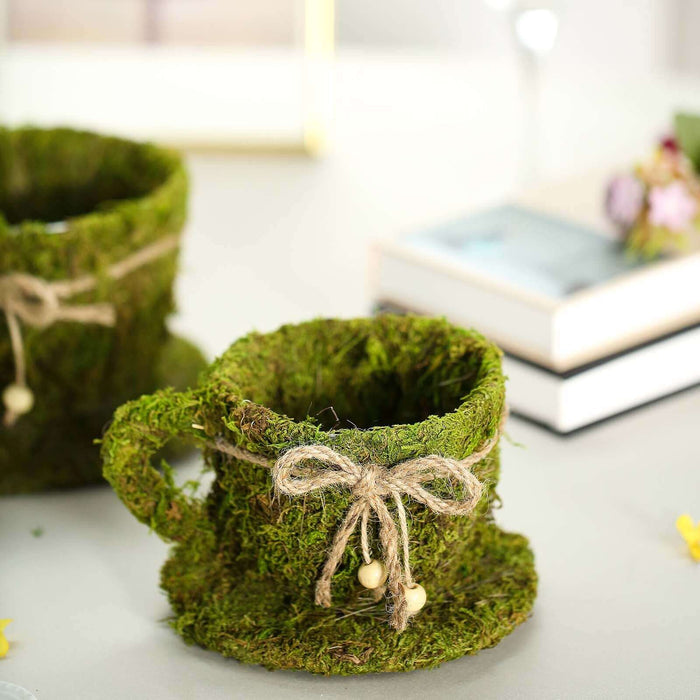 Moss-covered cup with twine bow and saucer on a table.