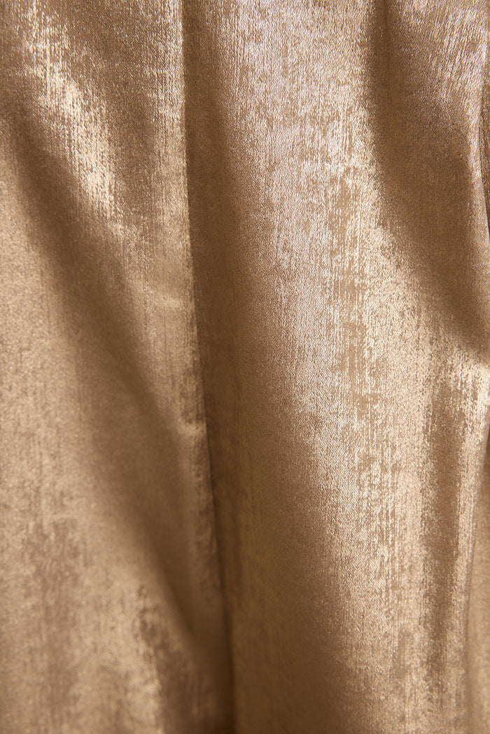 Close-up of the Waldorf trousers' metallic gold shimmer fabric, showing soft sheen and drape.