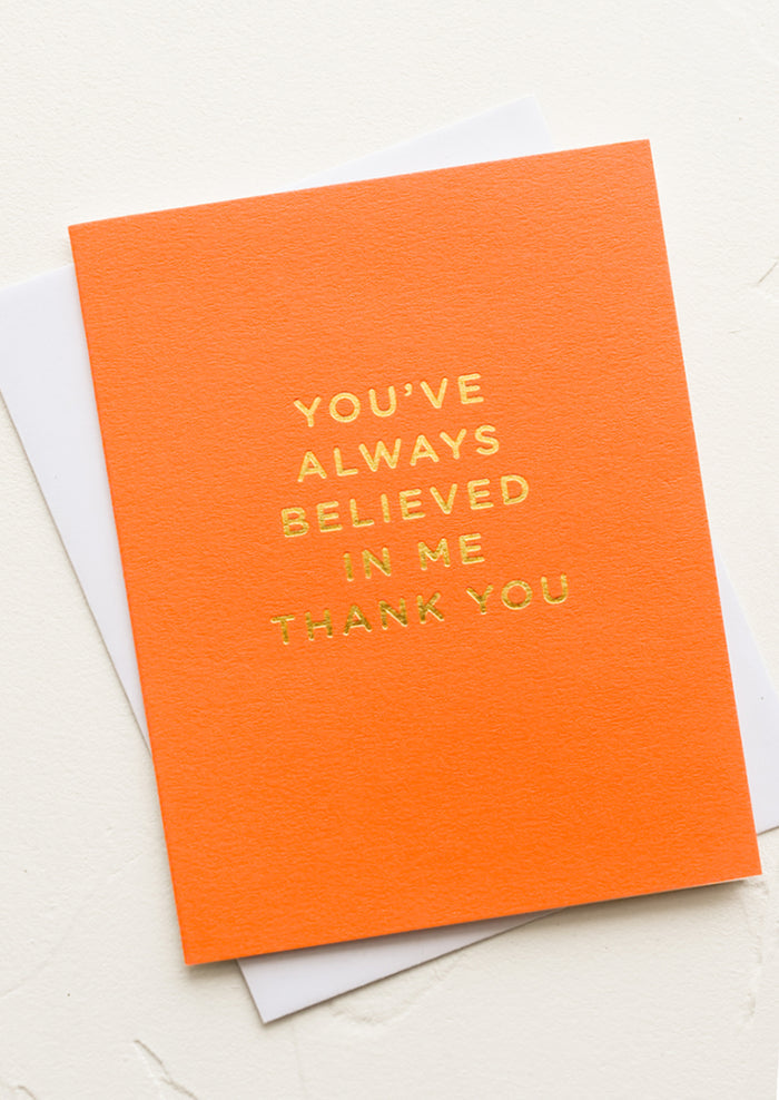 An orange greeting card with gold letters reading "You've always believed in me thank you".