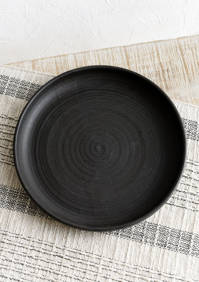 A shallow serving plate in matte black.