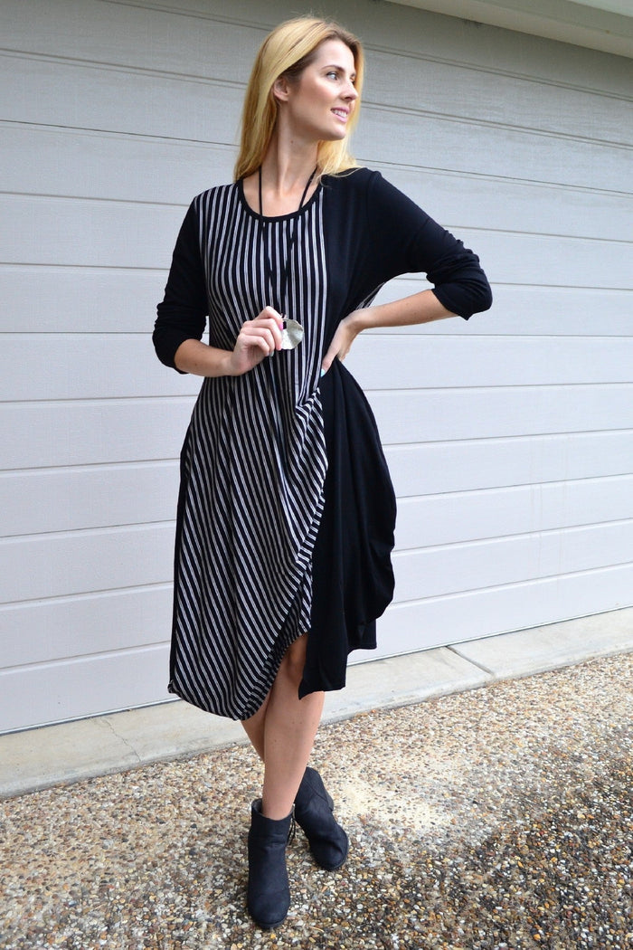 Black 3/4 sleeve stripe jersey tunic dress by Whispers, shown hanging with its relaxed fit and stylish striped pattern.