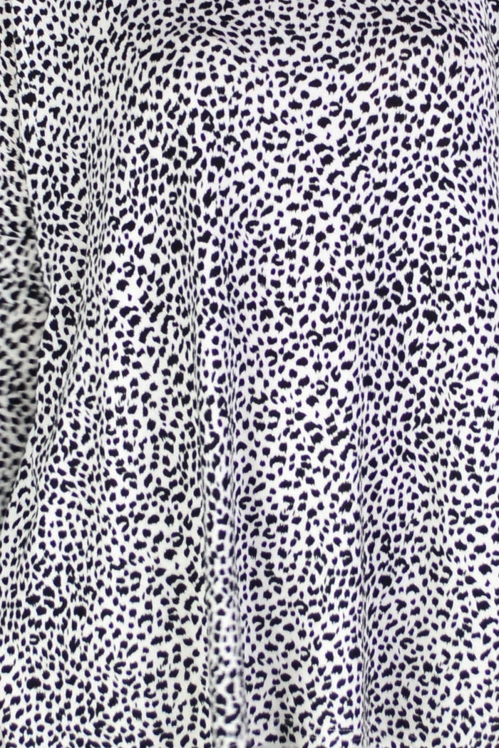 Black and white spot hi-low tunic top by Caroline Morgan displayed on a hanger with flowing fabric and stylish design.