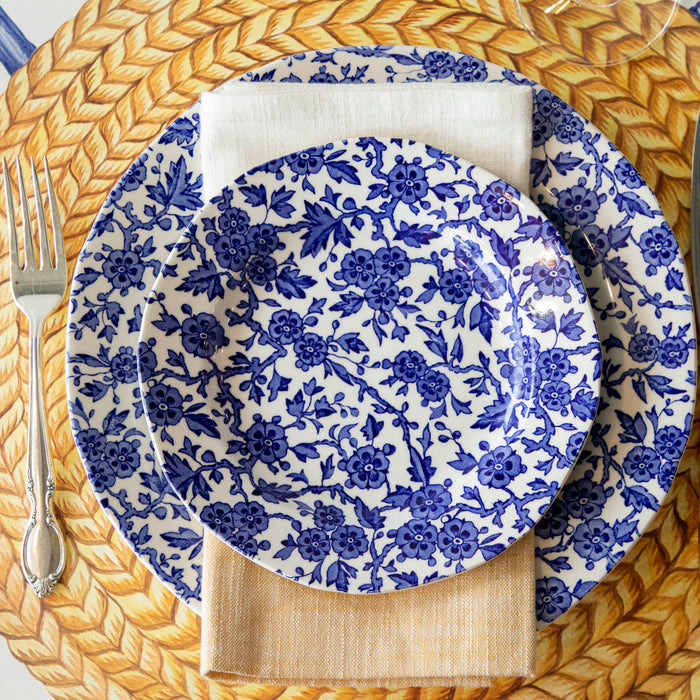 Burleigh Blue Arden plates on the Die-cut Braided Jute placemat with a folded napkin and a fork to the side.