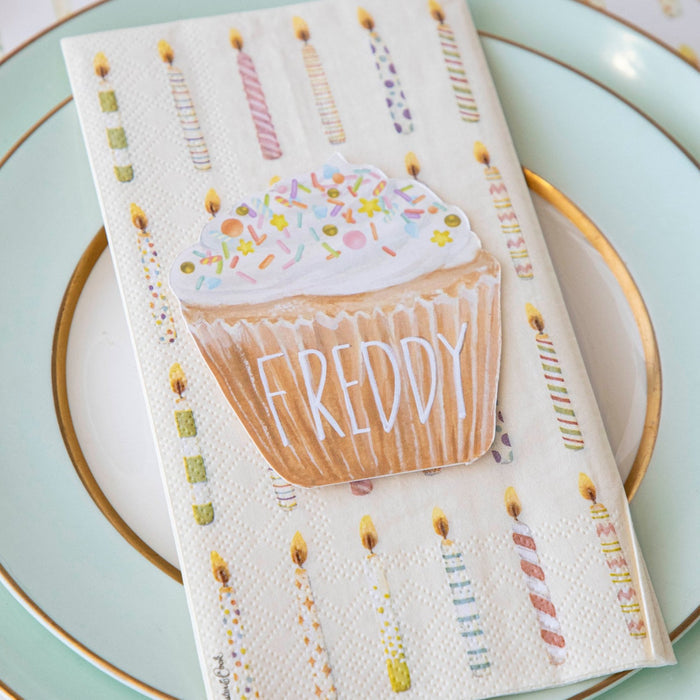A life-sized Hester & Cook Cupcake Place Card napkin featuring a cupcake and candles, perfect as a party place setting accessory.
