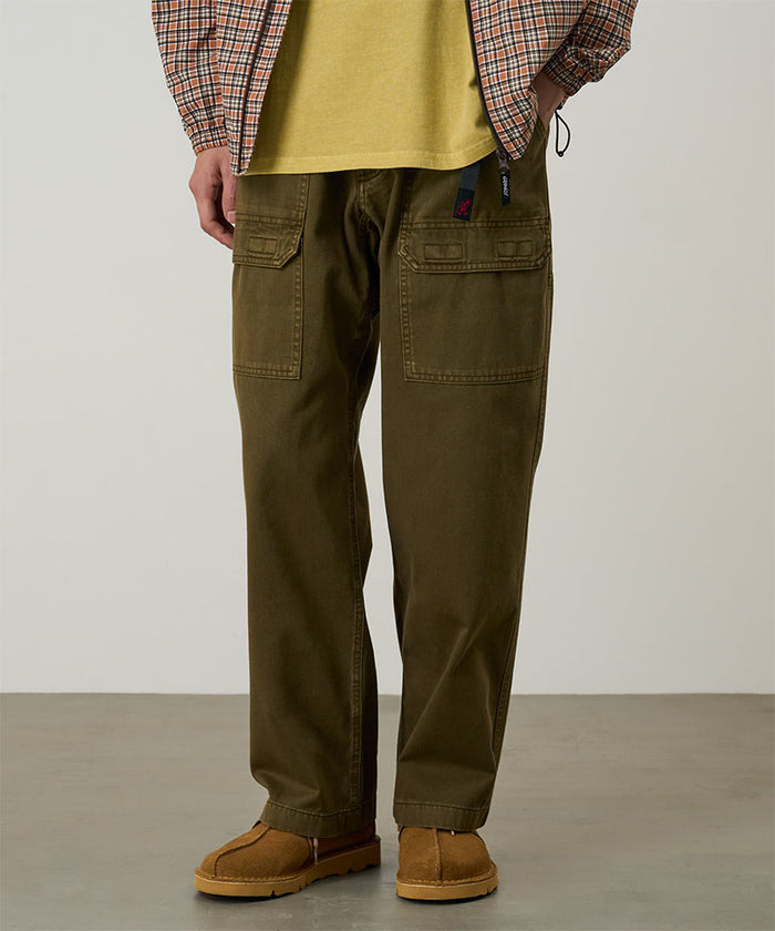 Model wearing bark pigment Gramicci EQT Pant and a plaid jacket on a light-tone background.