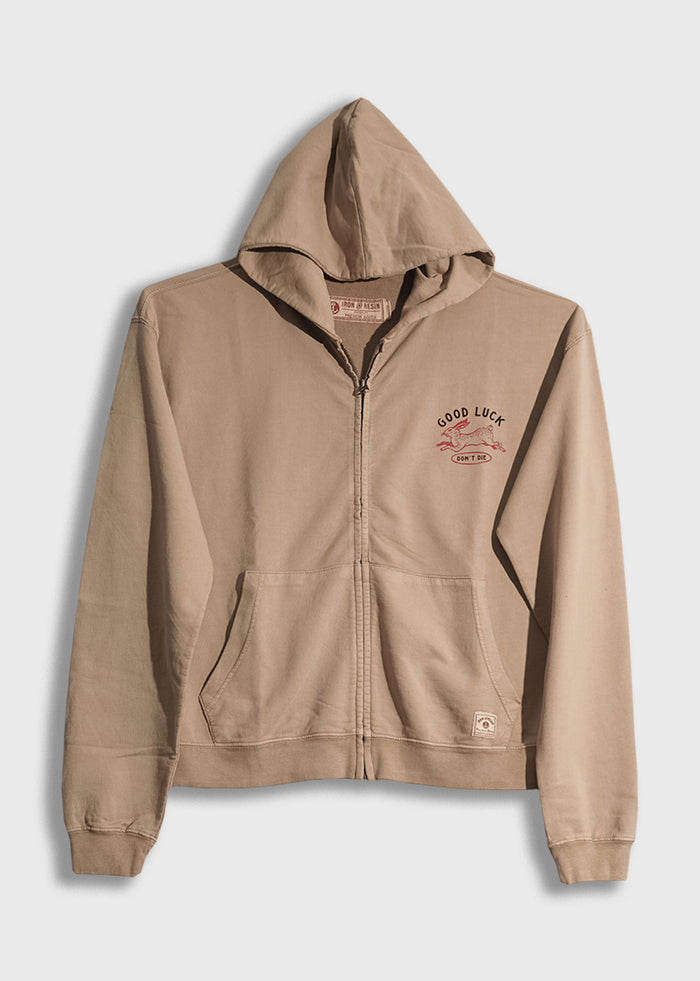 Beige zip-up hoodie with "Good Luck" and "Don't Die" text on chest, featuring a small graphic, displayed on a plain background.