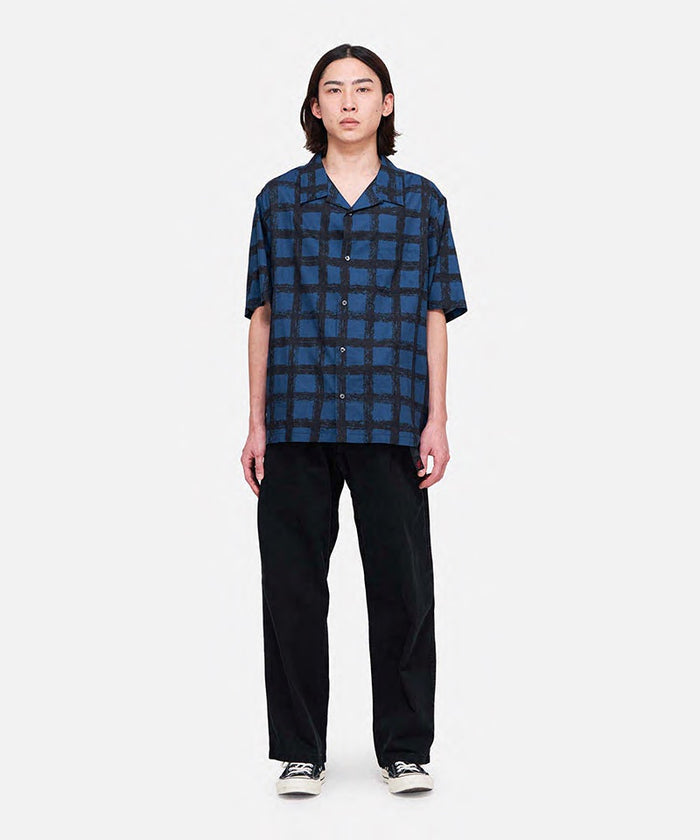 Model wearing black Gramicci Pant Straight Fit and a blue checkered shirt on a light-tone background.