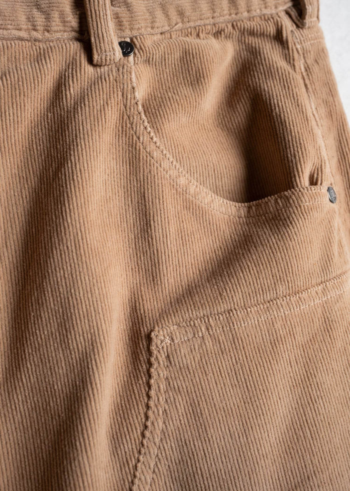 Close-up of brown corduroy pants pocket, showcasing texture and stitching details.