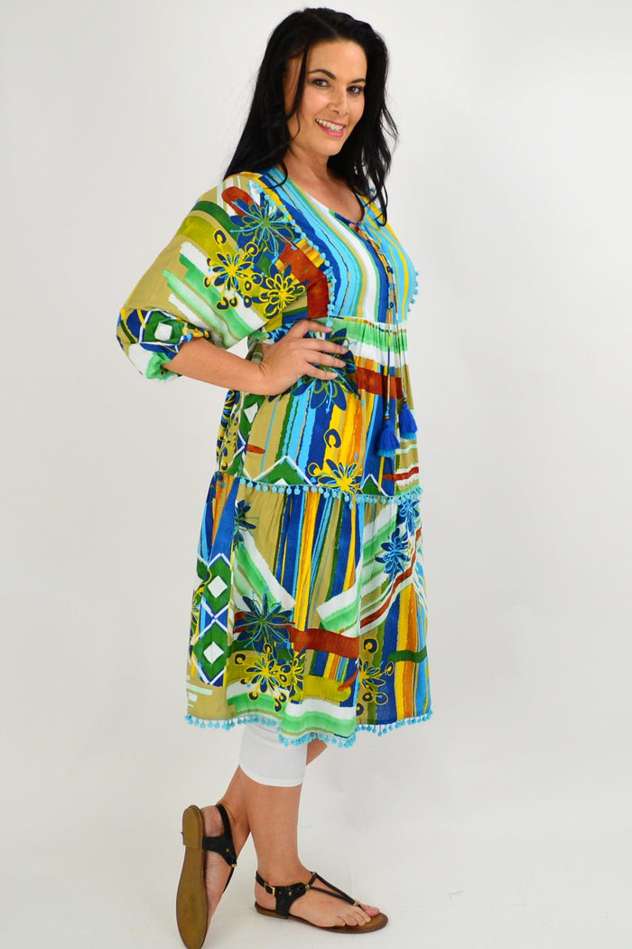 Orientique Malaga Midi Boho Tunic Dress displayed on a hanger with a vibrant, patterned fabric and flowing silhouette.