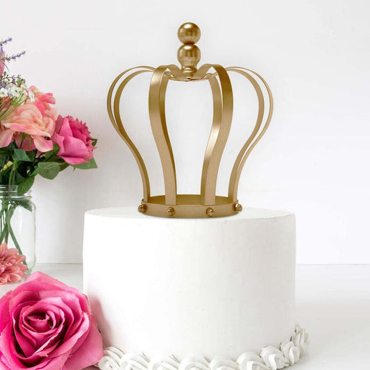 Gold crown cake topper on a white cake with pink flowers in the background.