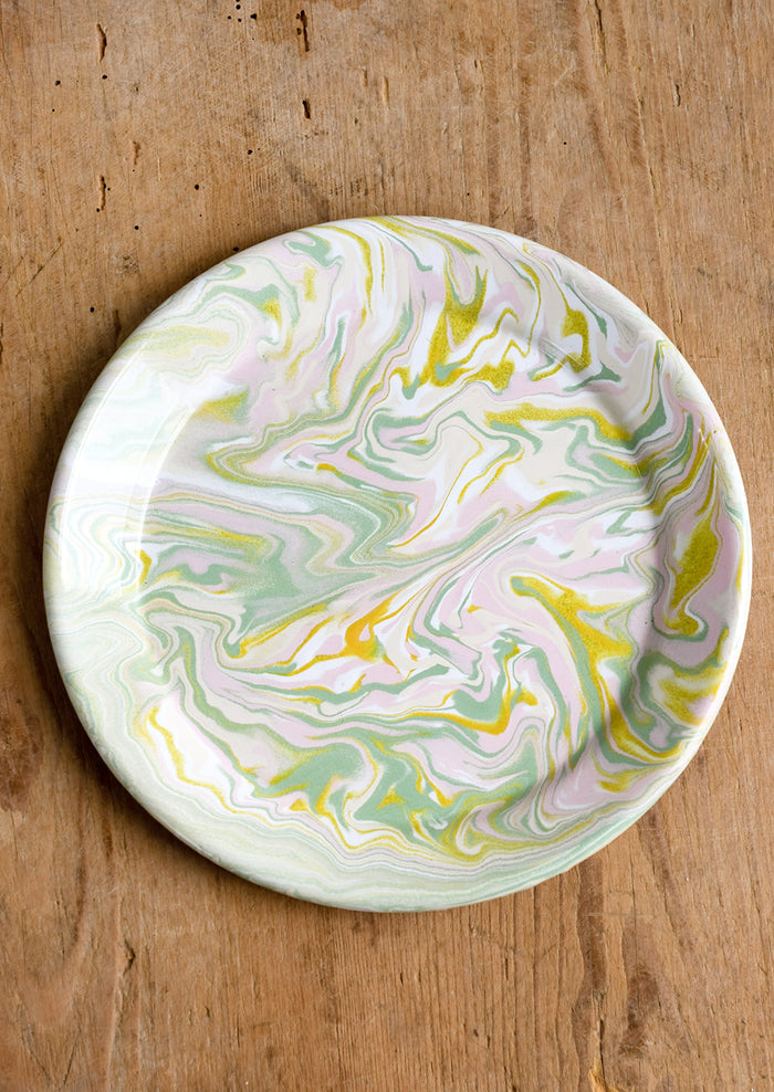 A round enamel plate with swirl pattern in pastel hues.
