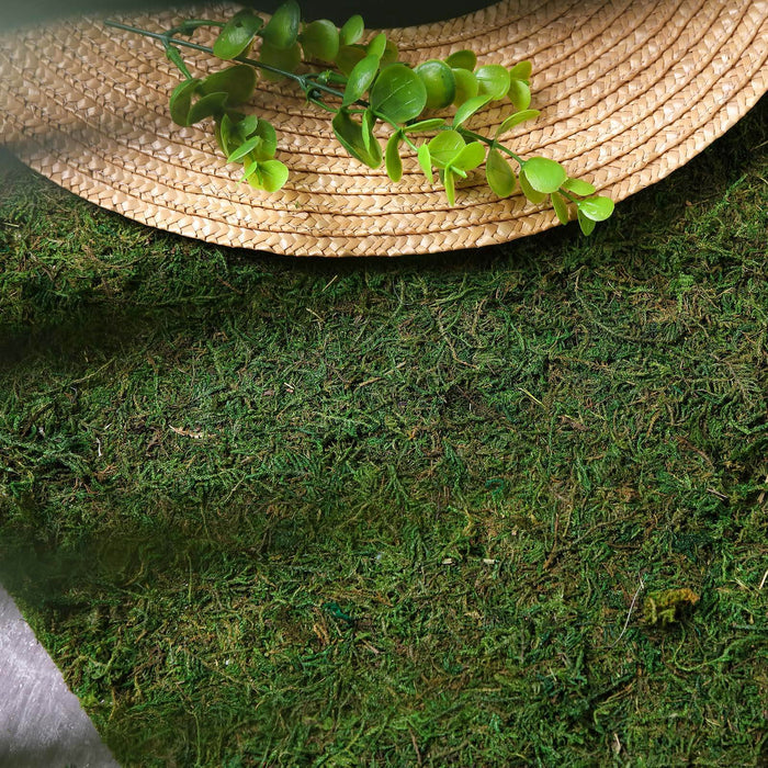 Green moss mat with woven straw placemat and artificial leaves.