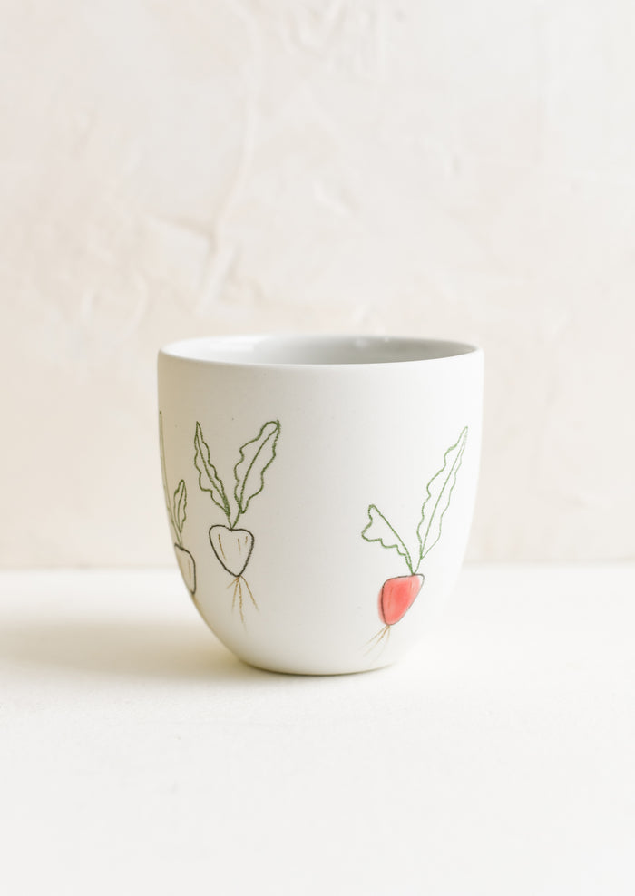 A small porcelain cup with hand drawn radishes.