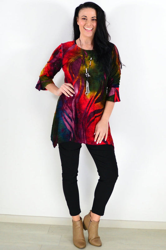 Colorful red forest print ladies tunic top by Whispers with long sleeves and a relaxed fit, shown on a hanger.