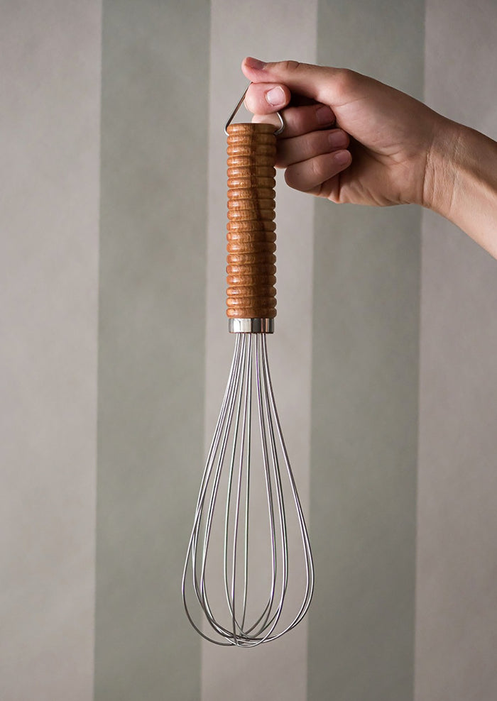 A stainless steel whisk with ribbed wooden handle.