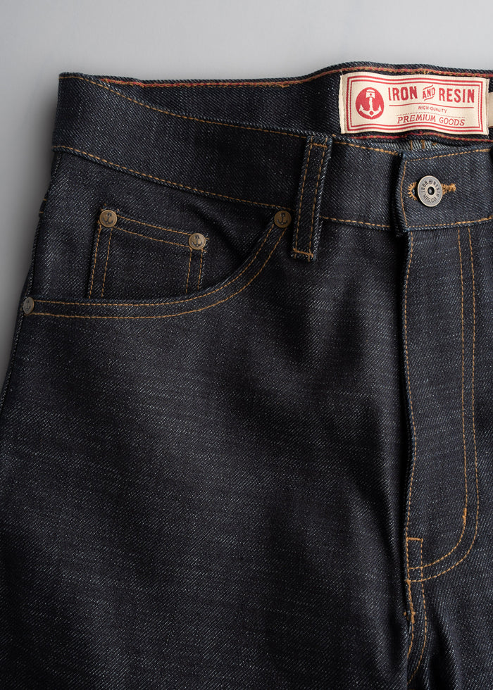 Close-up of Iron and Resin dark denim jeans with contrast stitching and branded label, showcasing premium quality craftsmanship.
