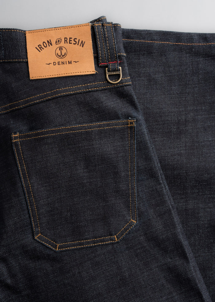 Dark denim jeans with a leather Iron and Resin label and visible stitching, showcasing classic style and craftsmanship.