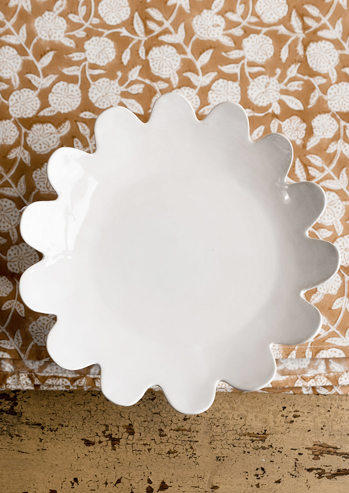 A pedestal riser in gloss white ceramic with scalloped plate shape.