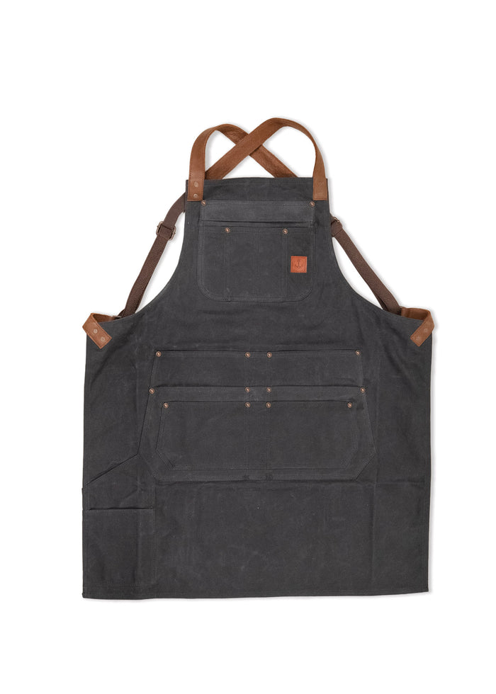 Dark canvas apron with brown leather straps and multiple pockets, designed for durability and functionality in various tasks.