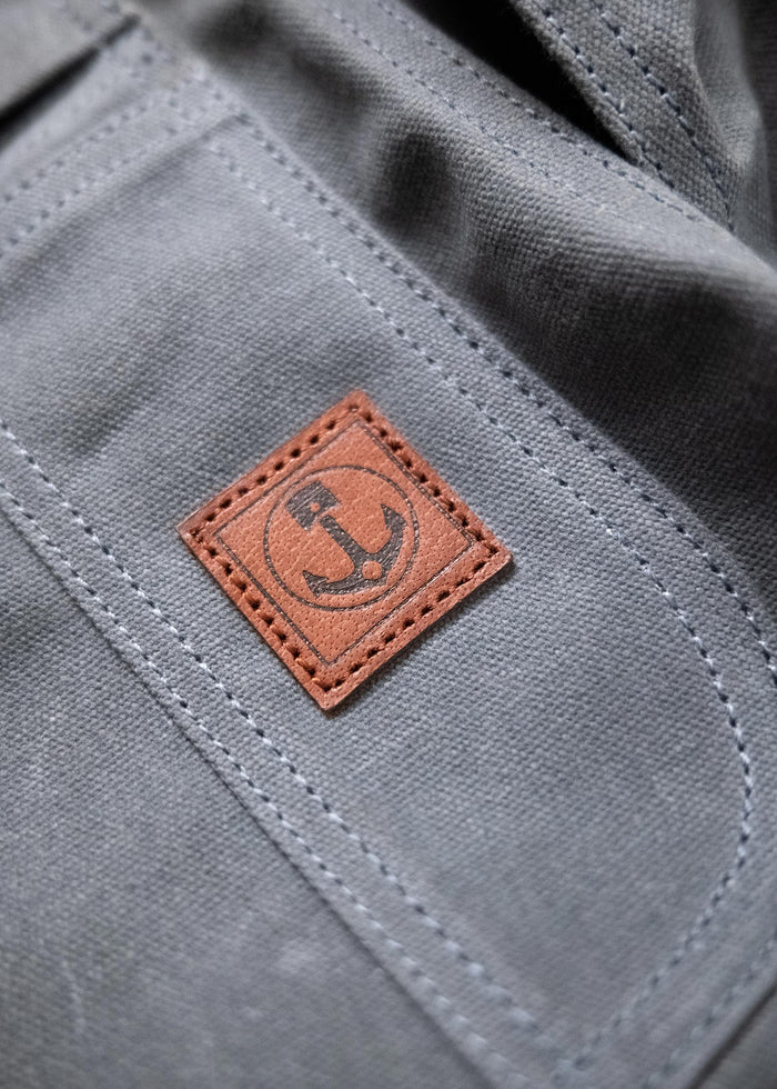 Gray fabric with a brown leather patch featuring an anchor design, highlighting nautical style and craftsmanship.