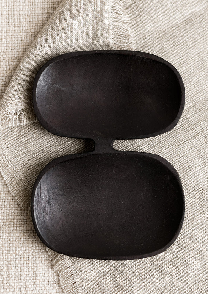 A double wide wooden dish with mirrored oval shape in blackened wood.