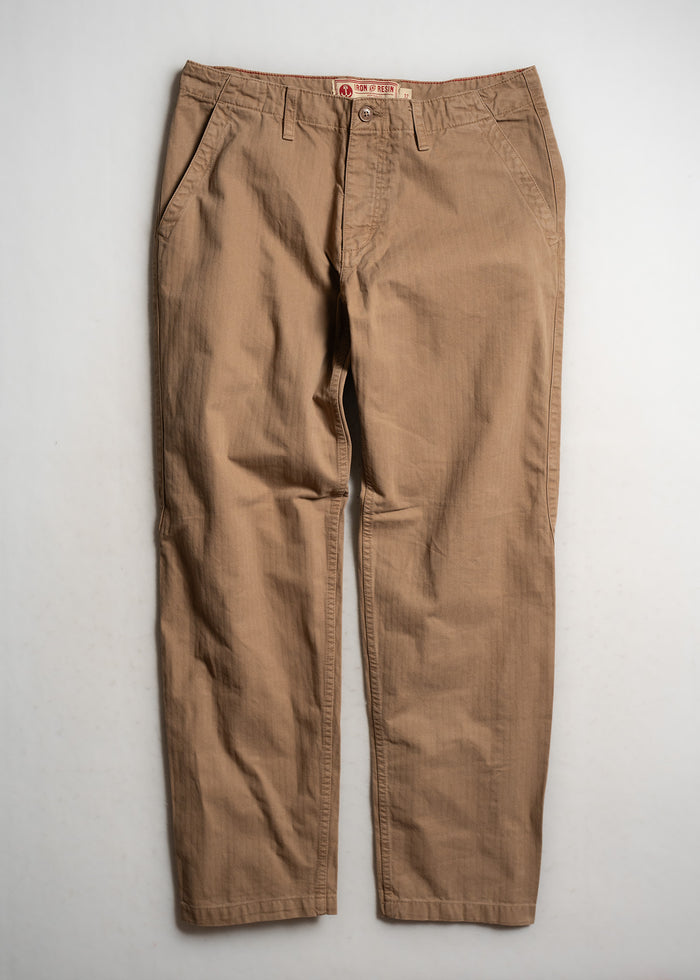 Tan khaki pants with front pockets and belt loops, laid flat on a white surface, showcasing casual style and simplicity.