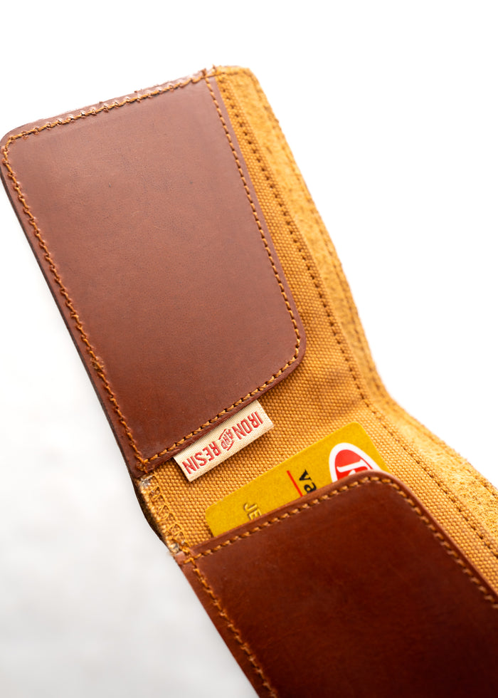 Brown leather wallet with visible stitching, open to show a yellow card and fabric lining, labeled "Iron Resin" inside.