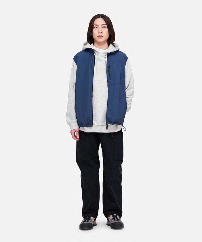 Model wearing black Gramicci Voyager Pants and a blue jacket on a light-tone background.
