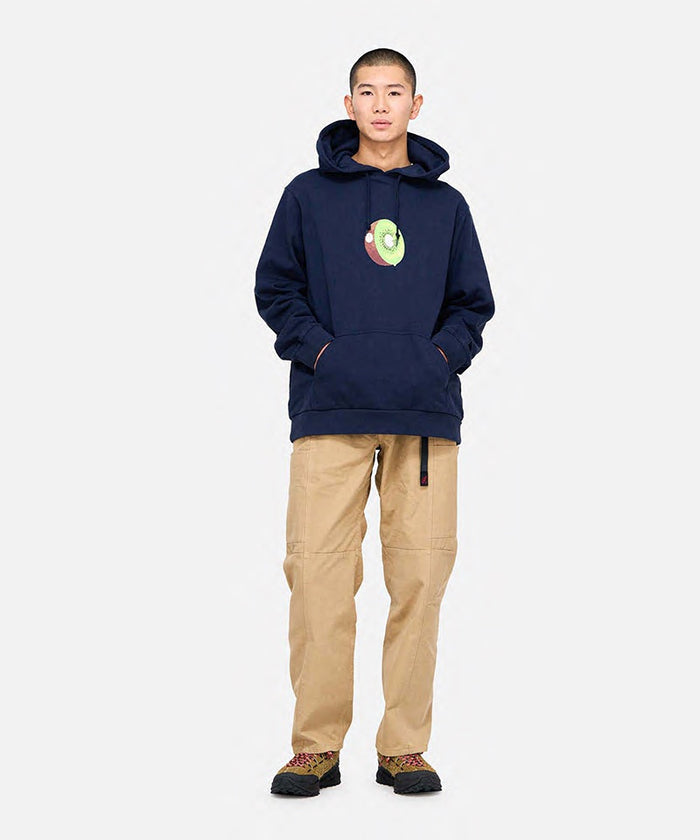 Model wearing chino colored Gramicci Voyager Pants and a navy hoodie on a light-tone background.