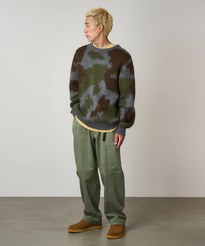 Model wearing sage colored Gramicci Voyager Pants and a mohair sweater on a light-tone background.