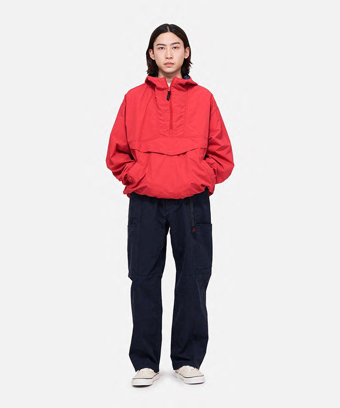 Model wearing double navy Gramicci Voyager Pants and a red jacket on a light-tone background.