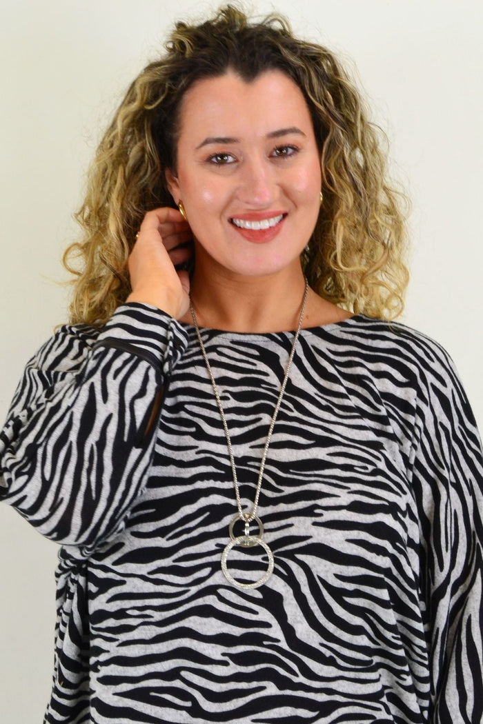 Caroline Morgan Zelma Zebra Relaxed Hi Low Hem Tunic Top with zebra print and flowy fit, displayed on a hanger against a neutral background.