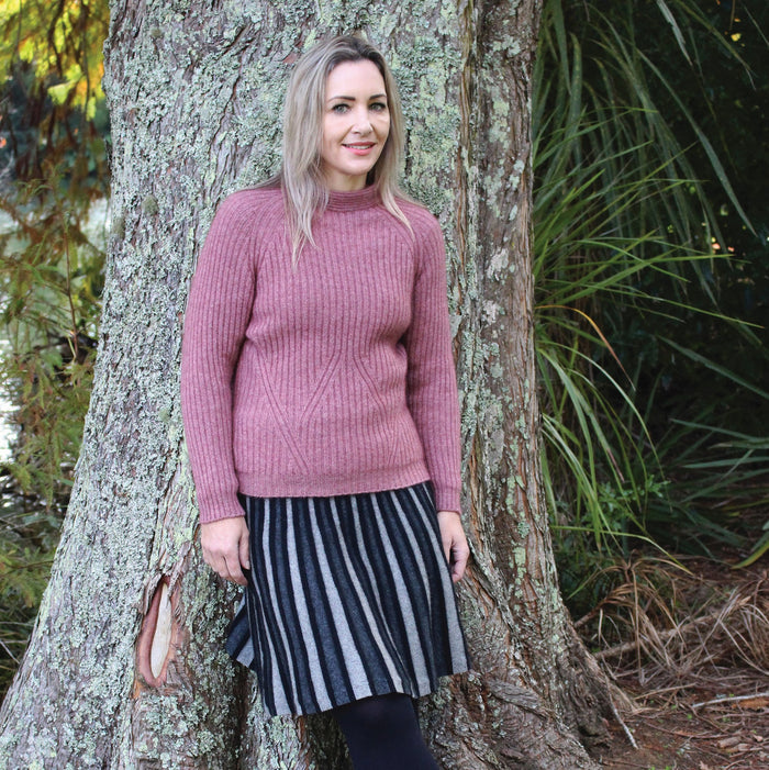 Woman wearing charcoal colour wedge skirt with pink jumper.